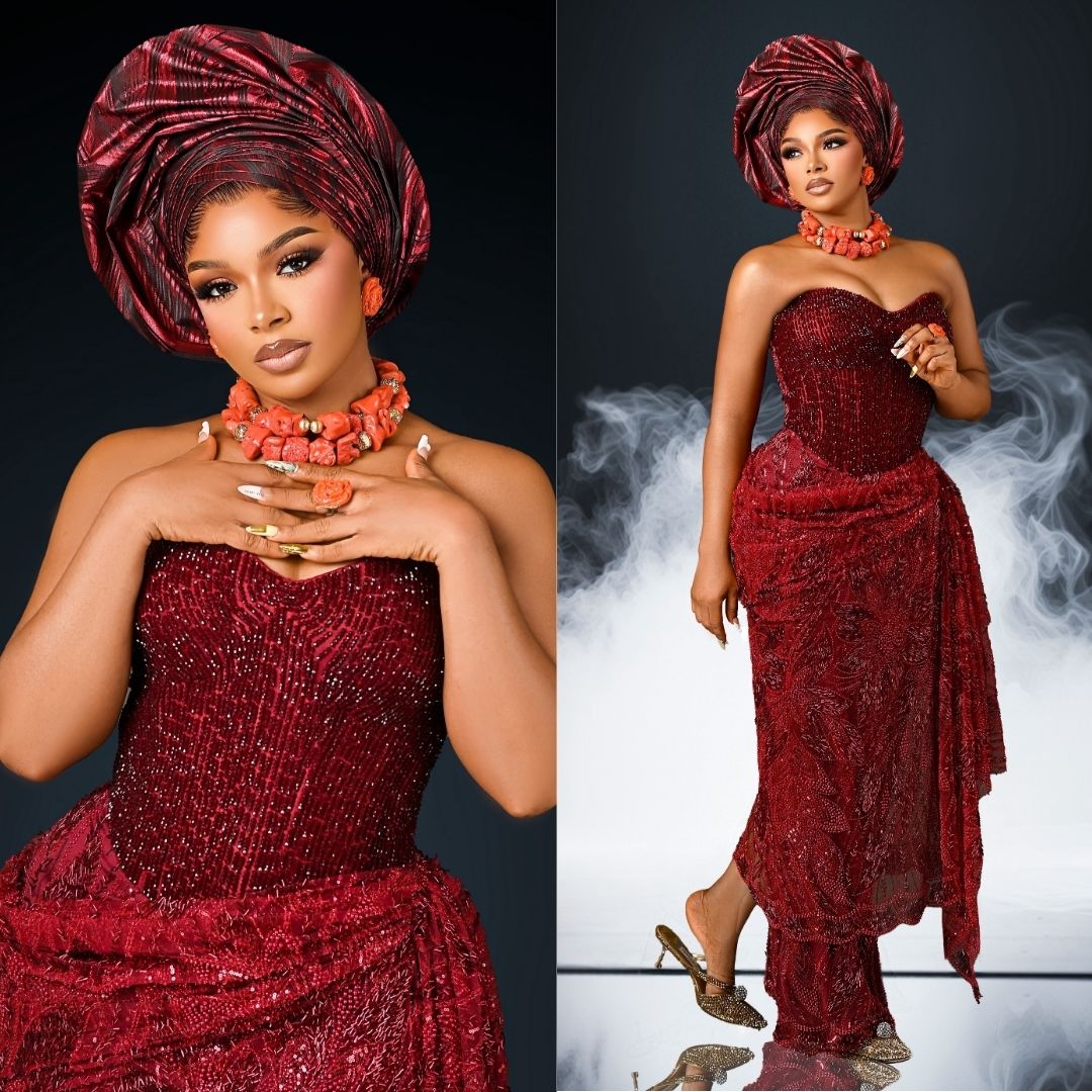 Liquorose wearing a strapless wine-red corset gown adorned with seed beading, a draped wrap skirt, traditional coral bead necklace, and a fan-pleated gele.