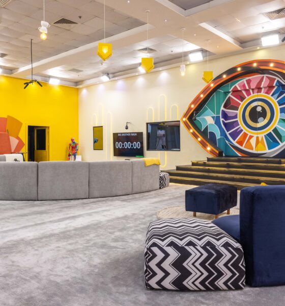 Main lounge in the Big Brother Naija Season 11 house featuring a large colourful illuminated Big Brother eye stage setup and digital countdown clock on