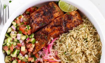 Kikifoodies garlic herb rice served in a bowl with pan-seared salmon, grilled shrimp, sliced avocado, pickled onions, and cucumber tomato salad.