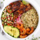 Kikifoodies garlic herb rice served in a bowl with pan-seared salmon, grilled shrimp, sliced avocado, pickled onions, and cucumber tomato salad.