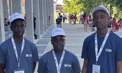 Don Anele Munachimso Marvelous, Egejurum Onyedikachi Ethan, and Chimdiebube Onwubiko wearing blue STEM Olympiad shirts and white caps outside Università Campus Bio-Medico di Roma.