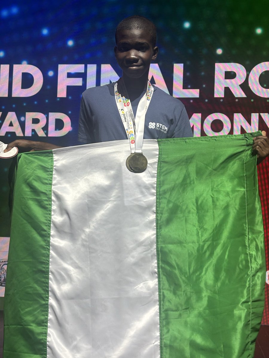 Don Anele Munachimso holding up the Nigerian flag while wearing his international science and mathematics gold medal in Rome.