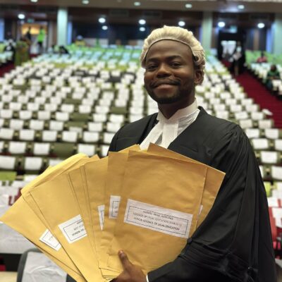 Israel Adeniyi Adekunle displaying a fan of brown award envelopes, including his Council of Legal Education Star Prize, at the Nigerian Law School.
