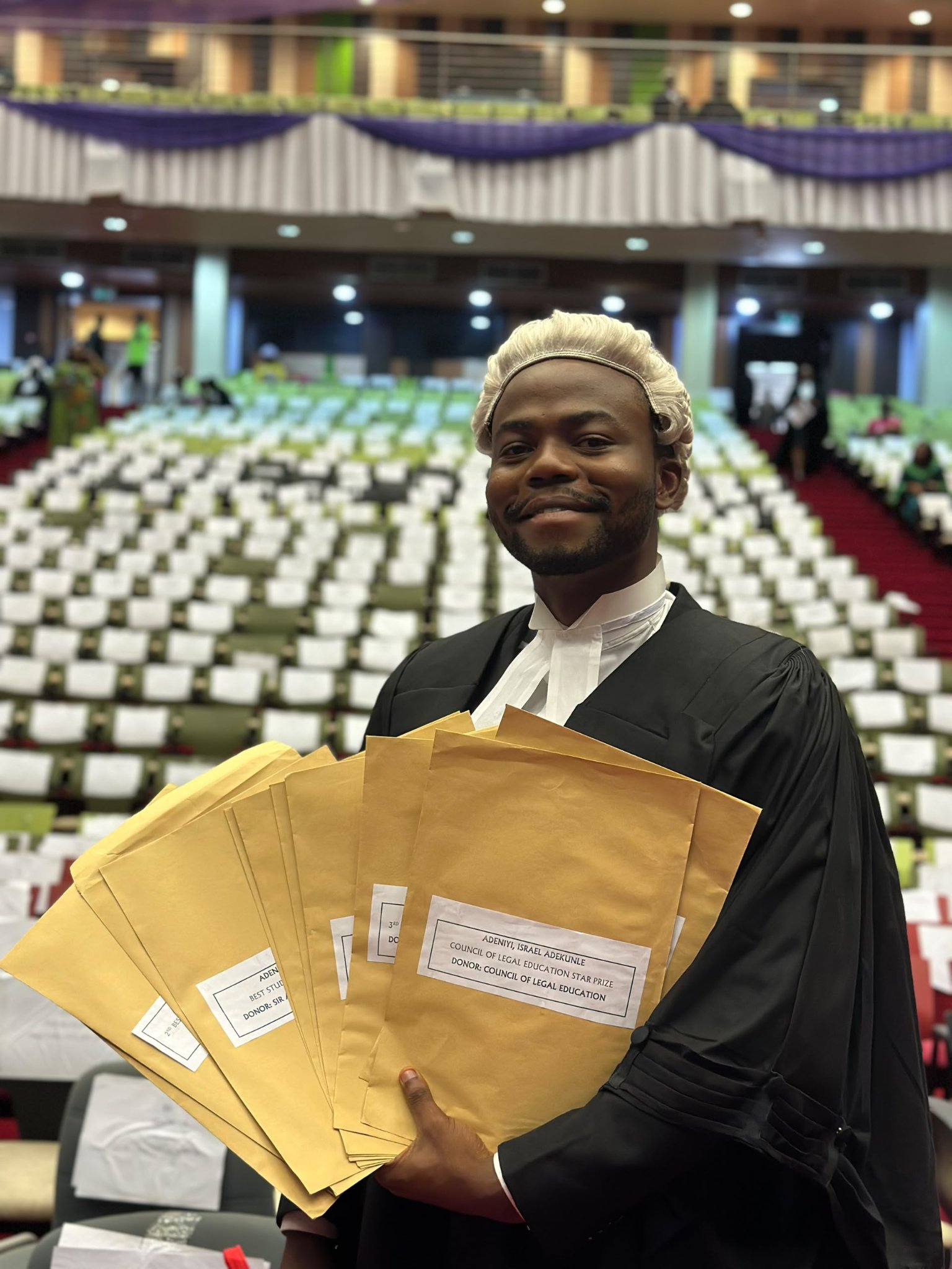 Israel Adeniyi Adekunle displaying a fan of brown award envelopes, including his Council of Legal Education Star Prize, at the Nigerian Law School.