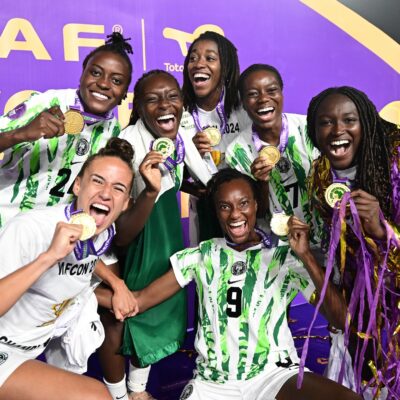 Nigeria Super Falcons players Asisat Oshoala, Ifeoma Onumonu, Deborah Abiodun, Ashleigh Plumptre, Toni Payne, and Jennifer Echegini displaying gold winner medals after defeating Morocco in the 2024 WAFCON final.
