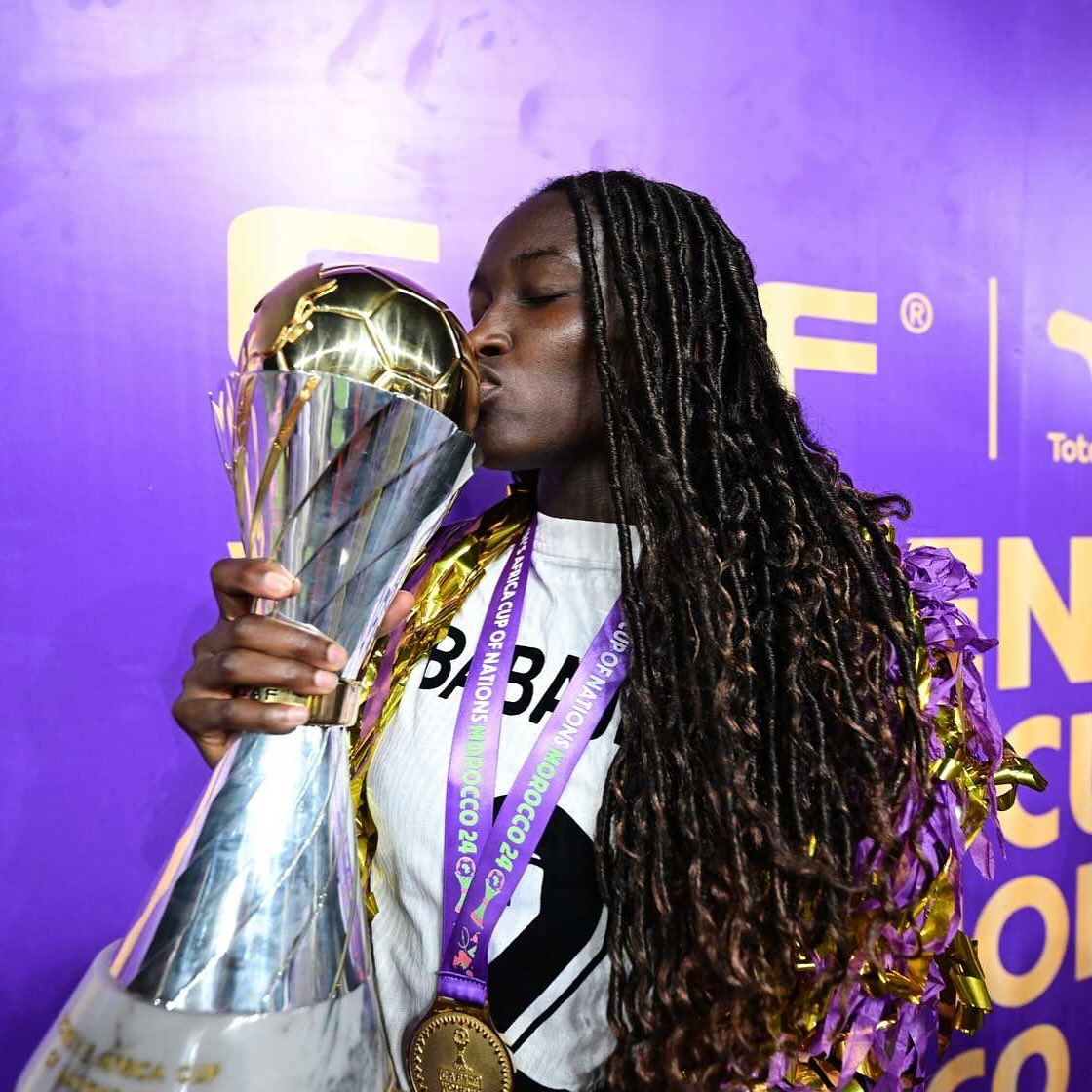Nigeria defender Ashleigh Plumptre kissing the official TotalEnergies CAF Women's Africa Cup of Nations trophy while wearing her gold medal after the 2024 final victory.