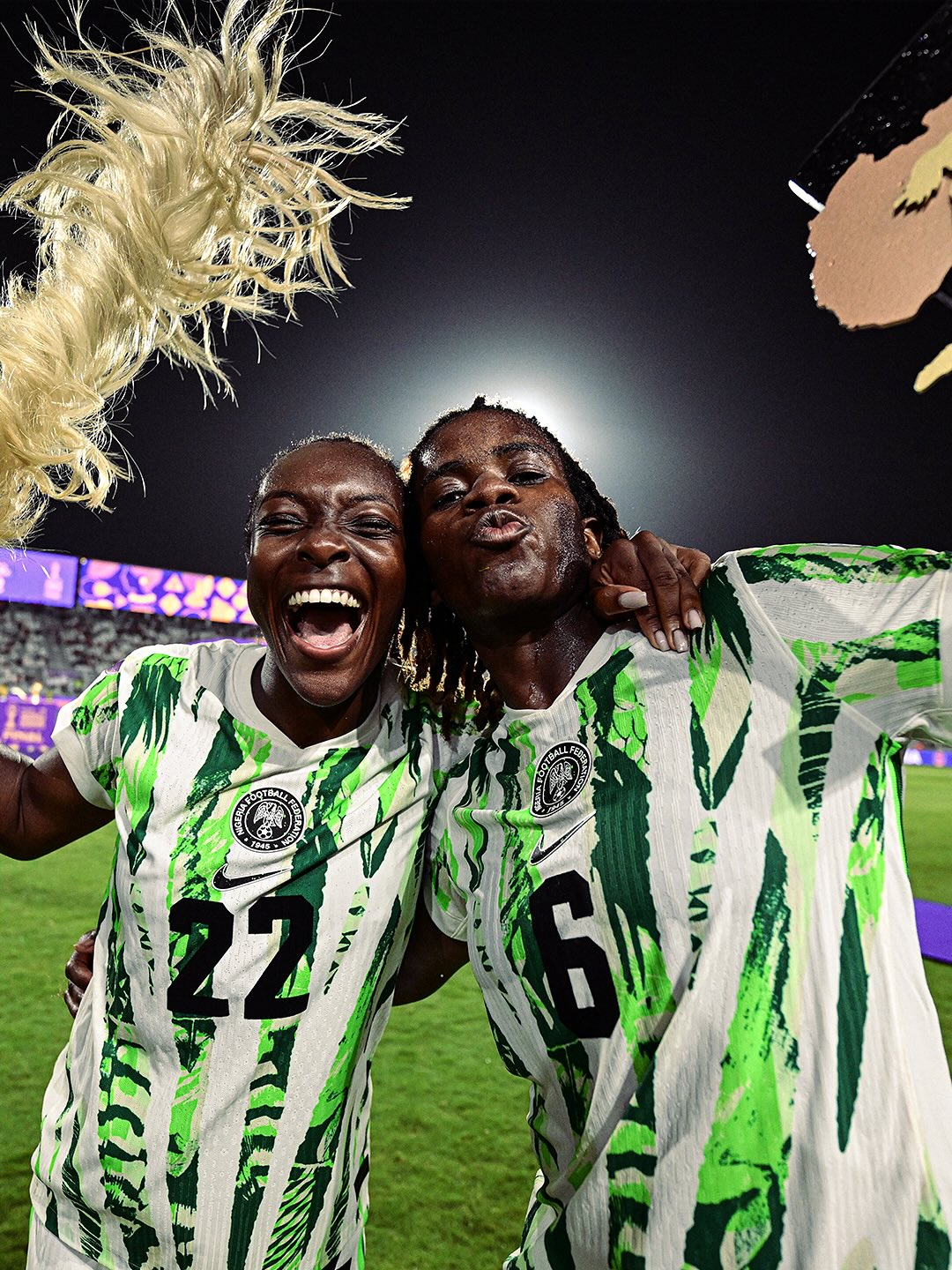 Nigeria Super Falcons defenders Michelle Alozie and Esther Okoronkwo celebrating on the pitch in green and white Nike jerseys following their Women’s Africa Cup of Nations final victory.