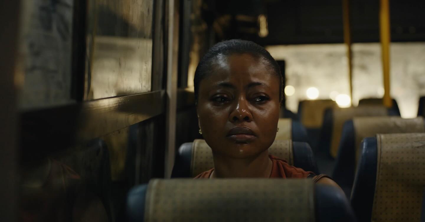 Actress Teniola Aladese crying with tears in her eyes while sitting inside a commercial bus in the movie We Must Begin Again Together.