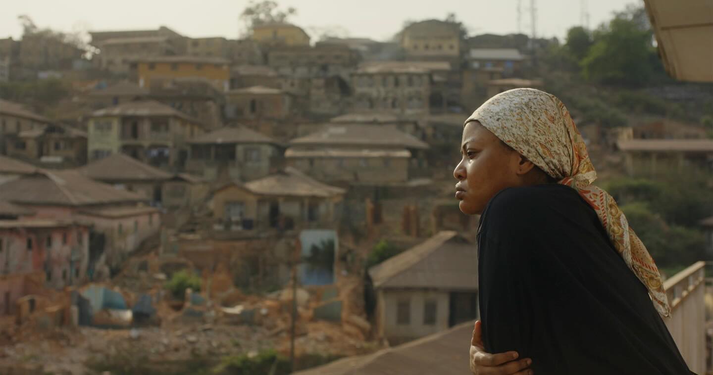Nigerian actress Teniola Aladese wearing a patterned headscarf and black top in the official teaser for the film We Must Begin Again Together.