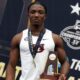 Kanyinsola Ajayi wearing his All-American medal and holding the NCAA championship trophy after running a 9.72-second 100m victory.
