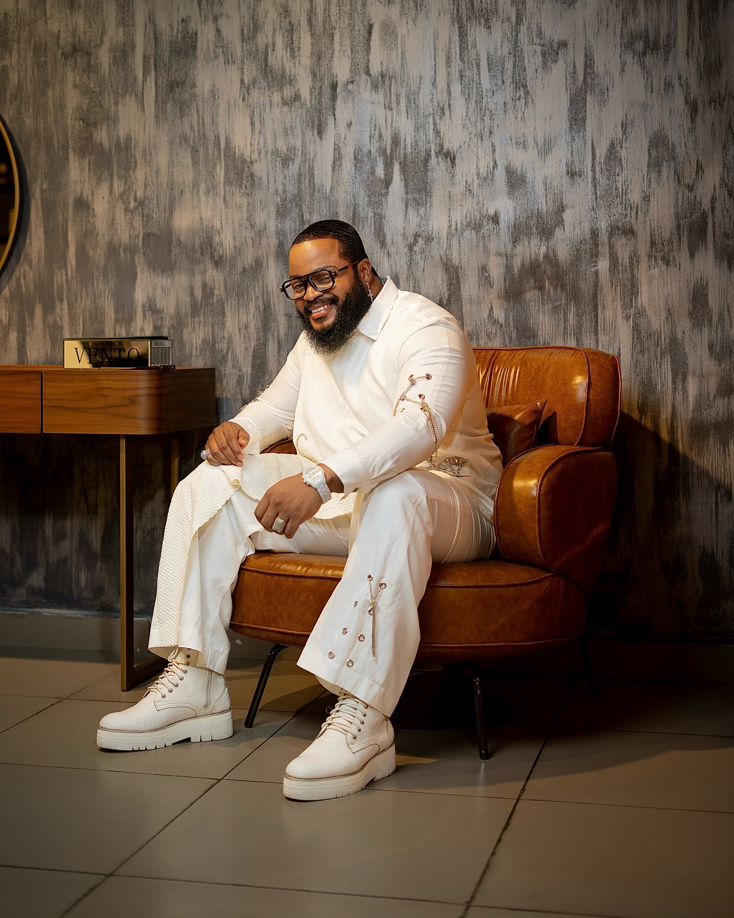 Whitemoney sitting in an armchair smiling after winning Big Brother Naija Season 6.