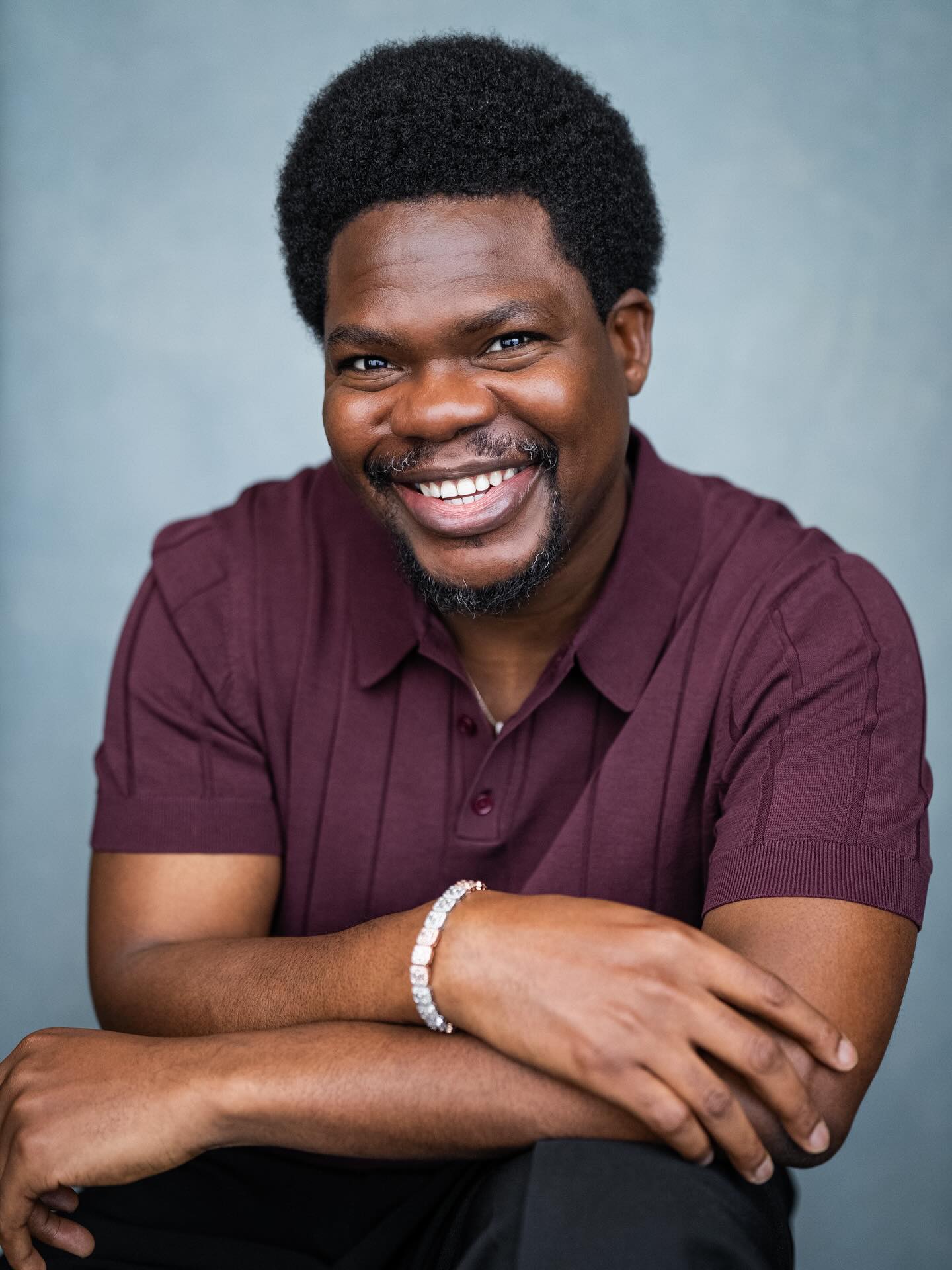 Nigerian actor Debo Adedayo, professionally known as Mr Macaroni, smiling in a maroon polo shirt for his official acting headshot.