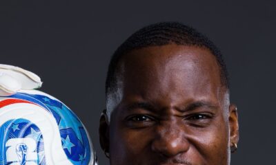 DR Congo goalkeeper Lionnel Mpasi shouting in celebration while holding the official FIFA World Cup 2026 match ball on his shoulder.