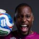 DR Congo goalkeeper Lionnel Mpasi shouting in celebration while holding the official FIFA World Cup 2026 match ball on his shoulder.