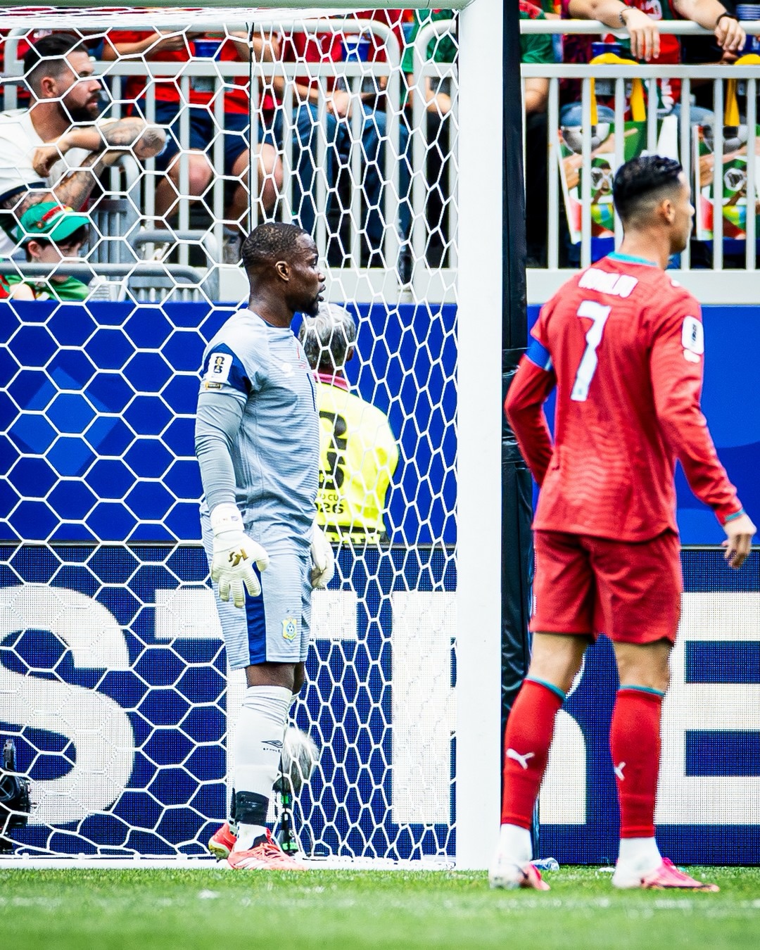 DR Congo goalkeeper Lionnel Mpasi inside the net looking out as Portugal's Cristiano Ronaldo walks past during their 2026 World Cup match.