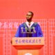 Nnabuike Chisom speaking into microphones at a wooden lectern with Chinese characters at Zhongnan University.