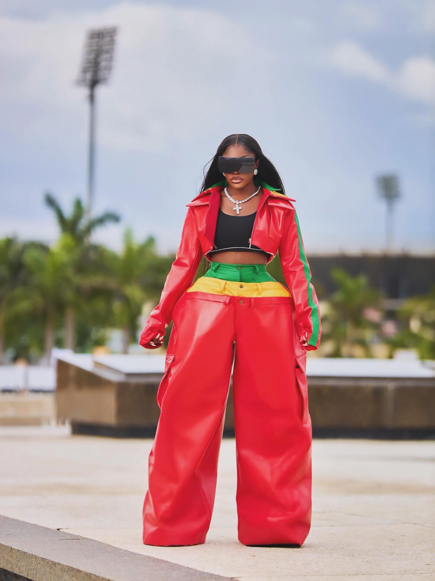 Nana Akua Addo wearing a cropped red leather moto jacket and red utility cargo pants featuring a triple-layered green, yellow, and red waistband.