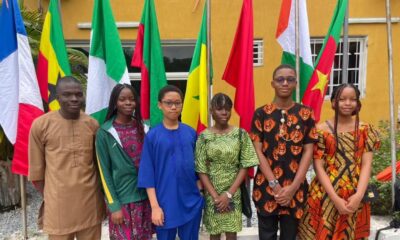 Six Team Nigeria secondary school student representatives dressed in traditional African attire standing in front of continental flags at the Pan-African Mathematics Olympiad in Yamoussoukro Ivory Coast.