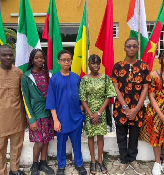 Six Team Nigeria secondary school student representatives dressed in traditional African attire standing in front of continental flags at the Pan-African Mathematics Olympiad in Yamoussoukro Ivory Coast.