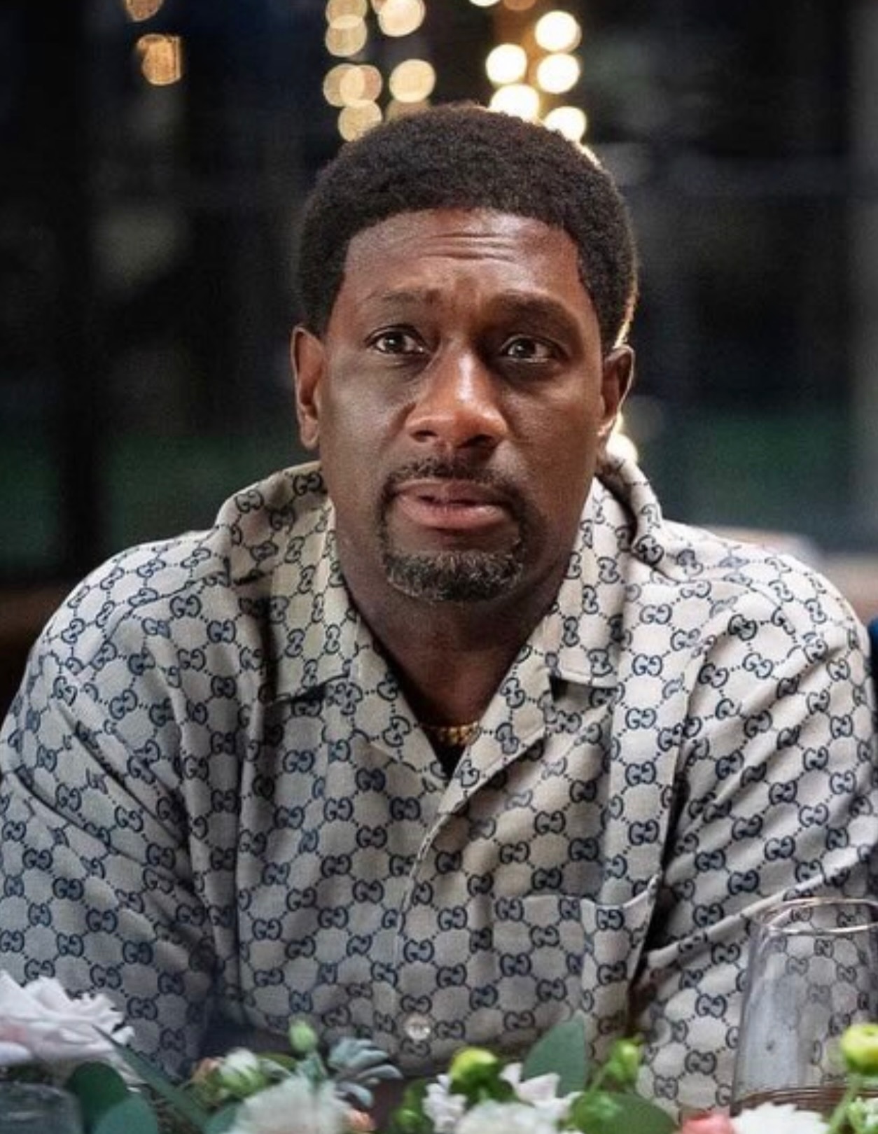 Actor Richard T. Jones reprising his role as Mike in a patterned silk shirt sitting at a dinner table in the Netflix movie sequel Why Did I Get Married Again?.