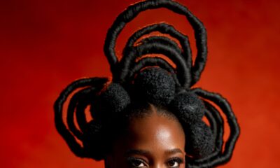 Gbubemi Ejeye looking directly at the camera wearing a structural natural hair creation made of large thread-wrapped loops and soft afro puffs.