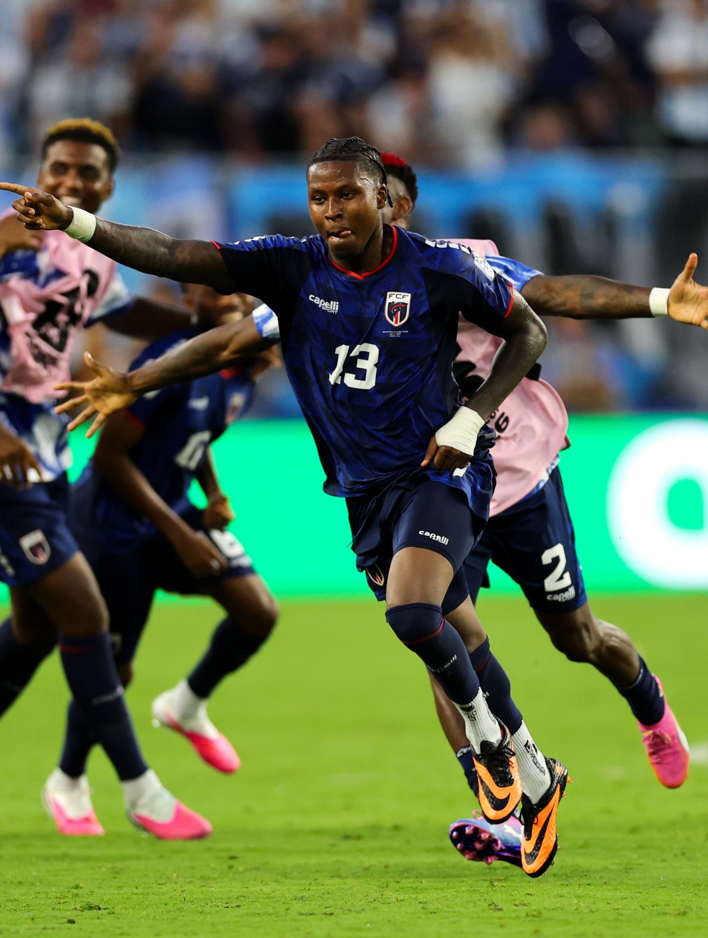 Sidny Lopes Cabral running across the pitch with arms outstretched celebrating his goal against Argentina.