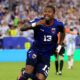 Sidny Lopes Cabral in the blue Cabo Verde kit sprinting down the football field during live match play.