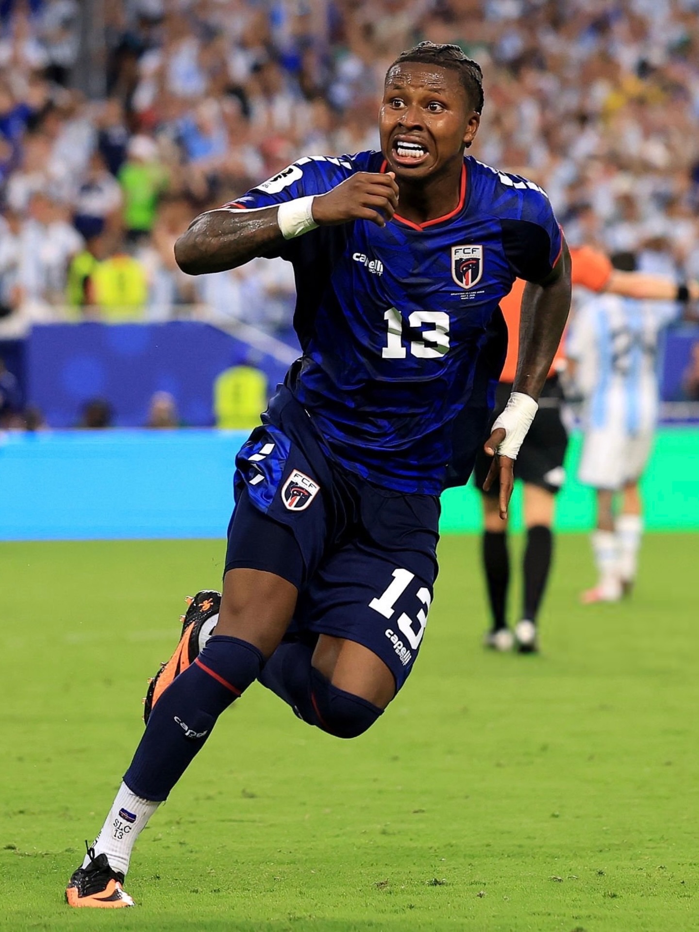 Sidny Lopes Cabral in the blue Cabo Verde kit sprinting down the football field during live match play.
