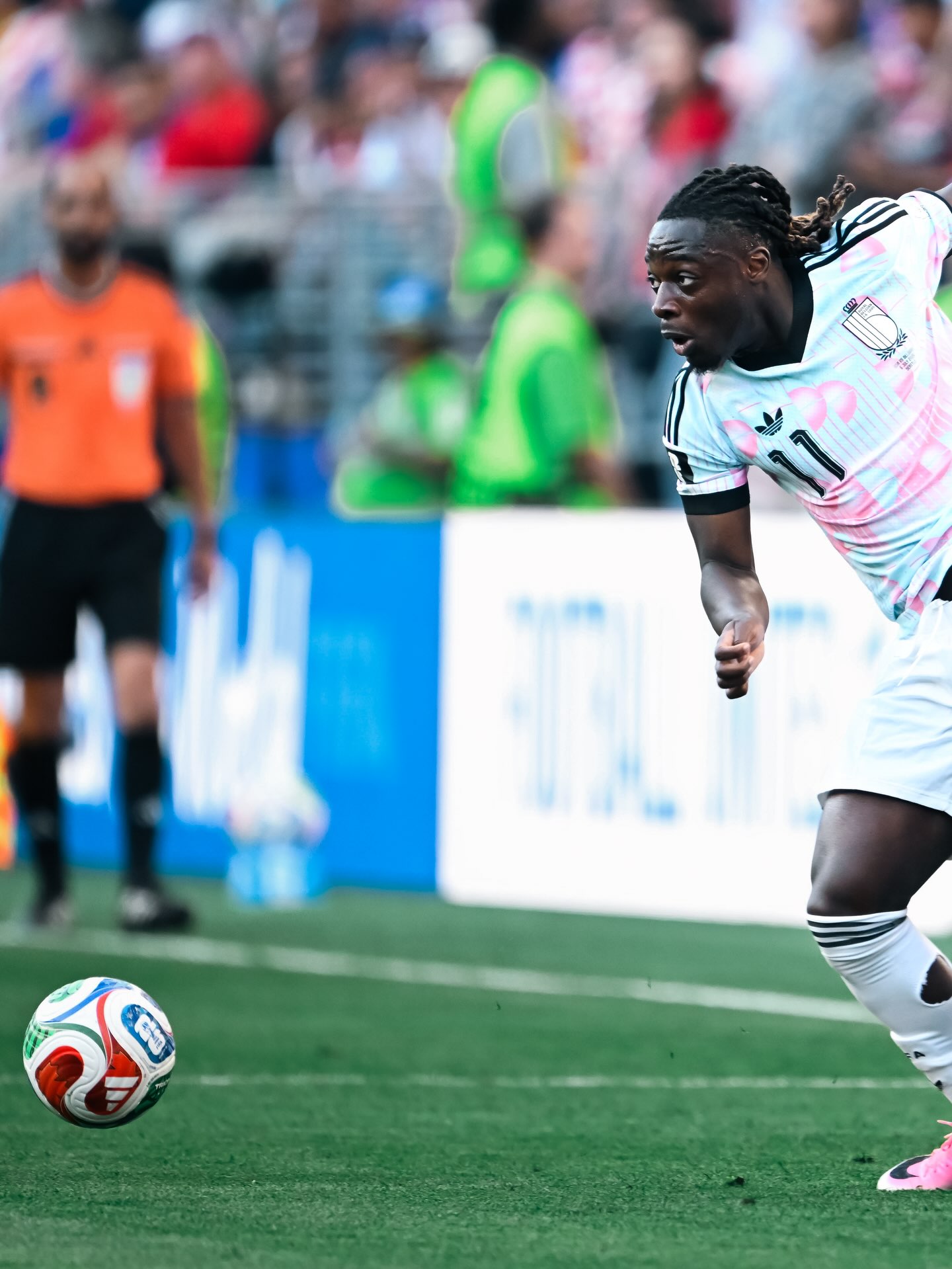 Winger Jeremy Doku of Ghanaian heritage sprinting past opponents while tracking the football during a 2026 FIFA World Cup knockout match for Belgium.