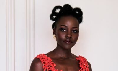 Lupita Nyong'o in a coral-red open-work lace Chanel dress, with architectural natural hair loops and smoky eye makeup by Nick Barose.