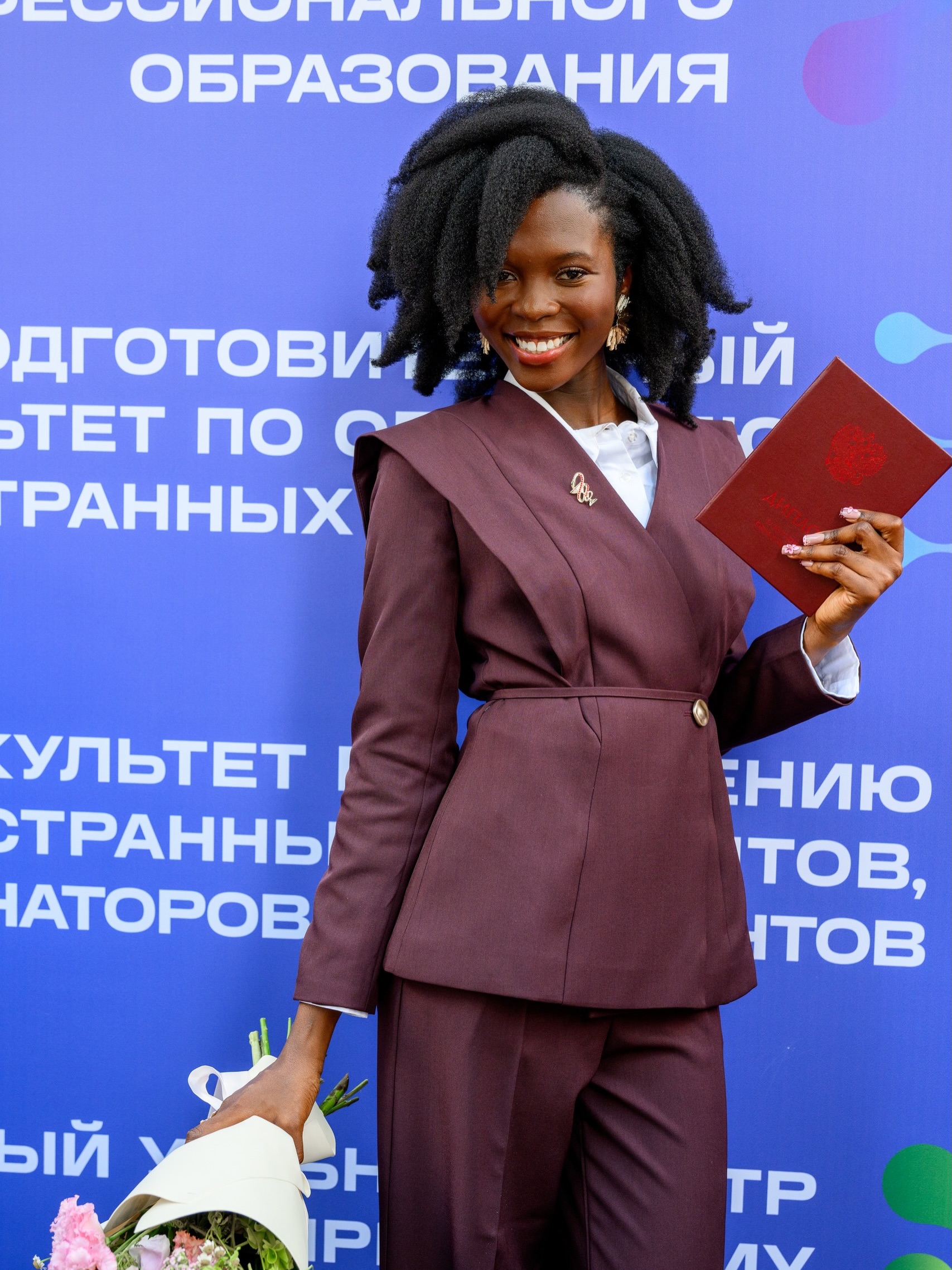 Dr Dorcas Akanbi holds her medical degree diploma and a flower bouquet at her graduation in Russia.