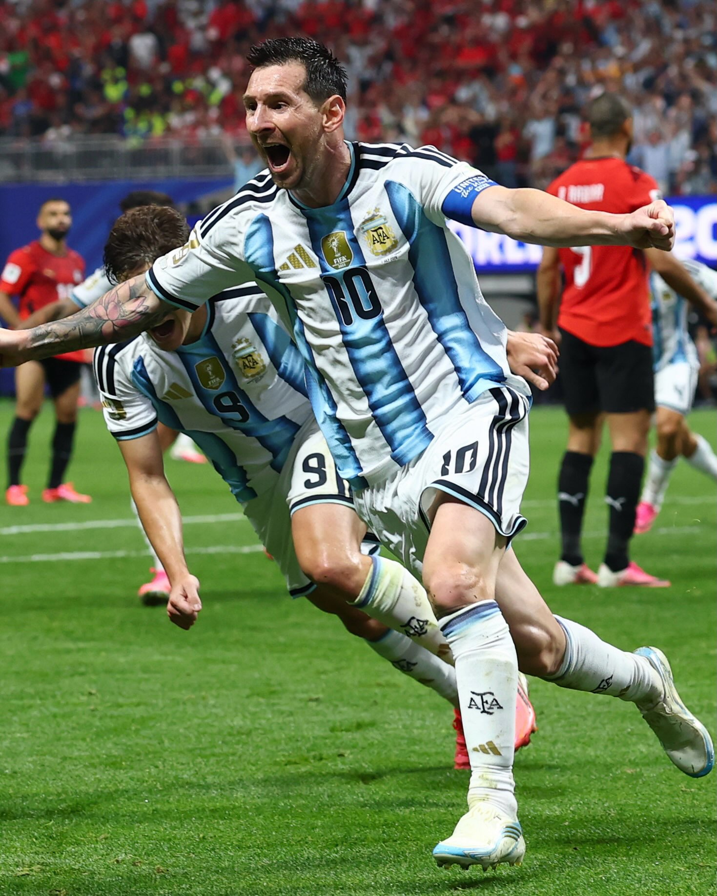Lionel Messi shouting in celebration after scoring the equalising goal against Egypt alongside teammate Julián Álvarez.