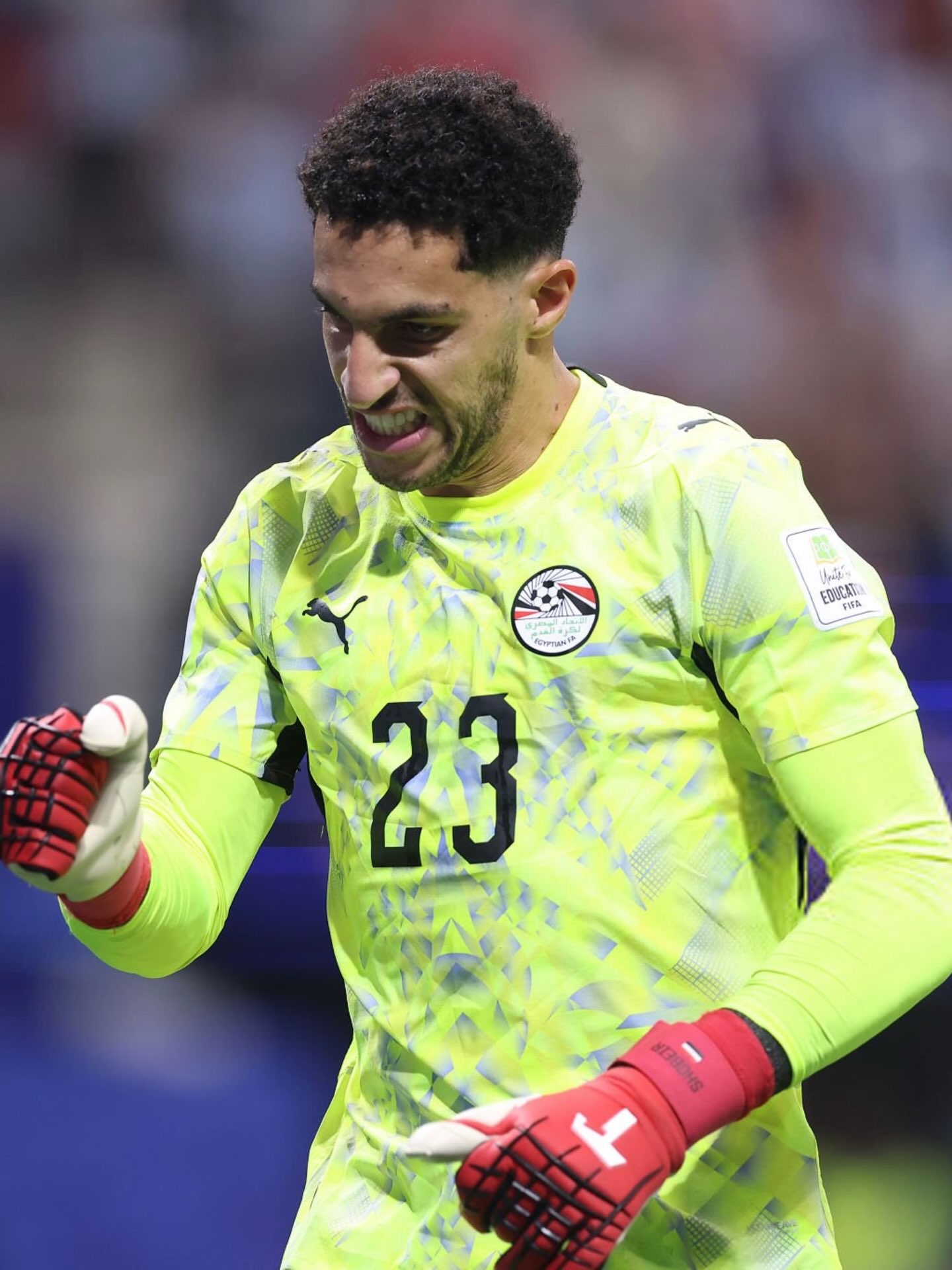 Egypt goalkeeper Mostafa Shobeir wearing a bright yellow jersey and celebrating a crucial save against Argentina.