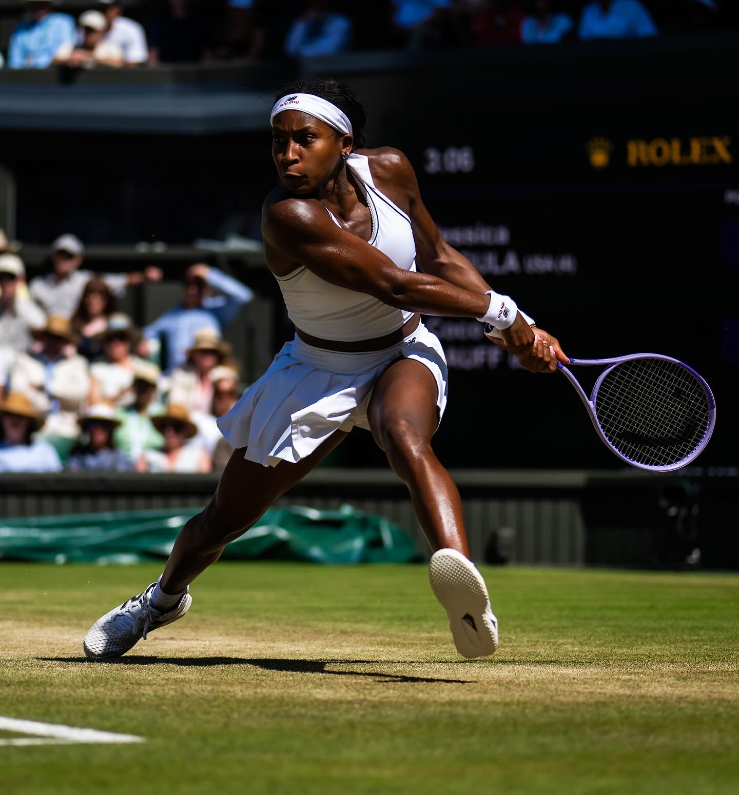 Coco Gauff hitting a two-handed backhand from the baseline on the grass at Wimbledon Centre Court.