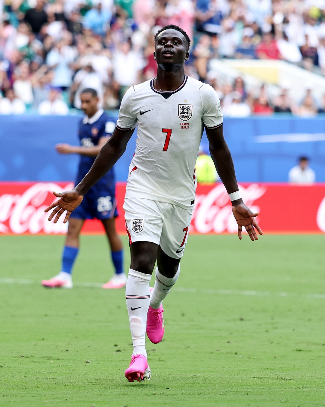 Bukayo Saka runs across the football pitch with his arms outstretched in celebration during the England vs France match.