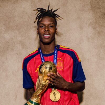 Nico Williams wears his Spain national team kit and winner medal while holding the FIFA World Cup trophy.