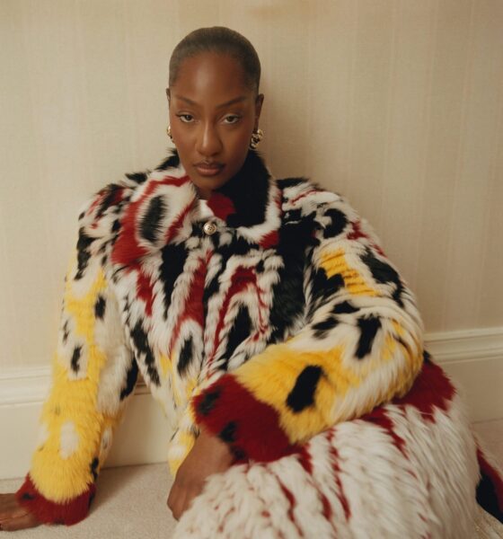 Tems wearing a patterned black, white, red, and yellow Chanel patchwork lambskin coat with gold LO Collections x Alex & Trahanas hoop earrings.