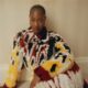 Tems wearing a patterned black, white, red, and yellow Chanel patchwork lambskin coat with gold LO Collections x Alex & Trahanas hoop earrings.