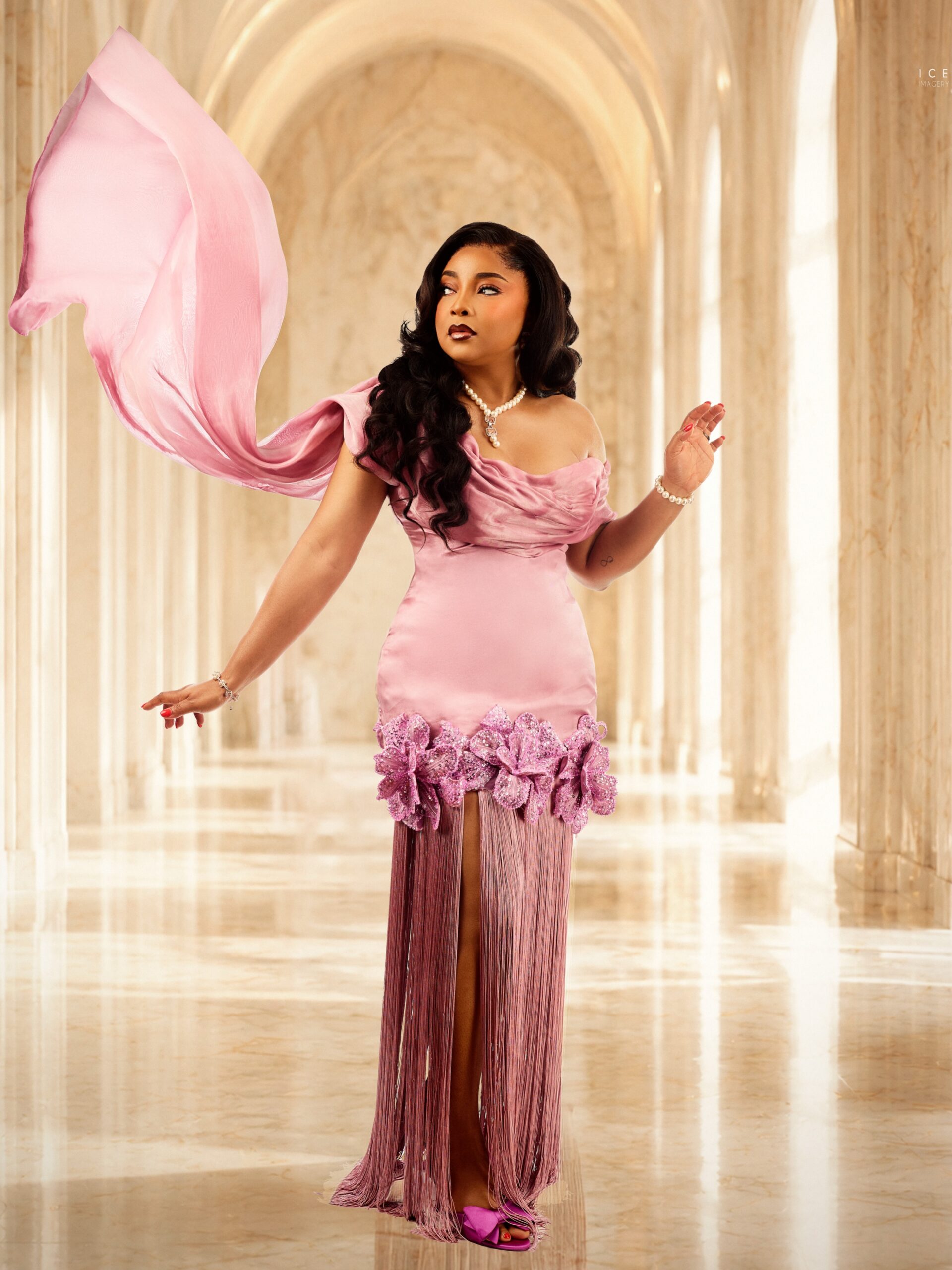 Actress Linda Ejiofor-Suleiman in a custom rose-pink gown with a long fringe skirt, 3D purple sequins flowers, and a flowing chiffon sash.