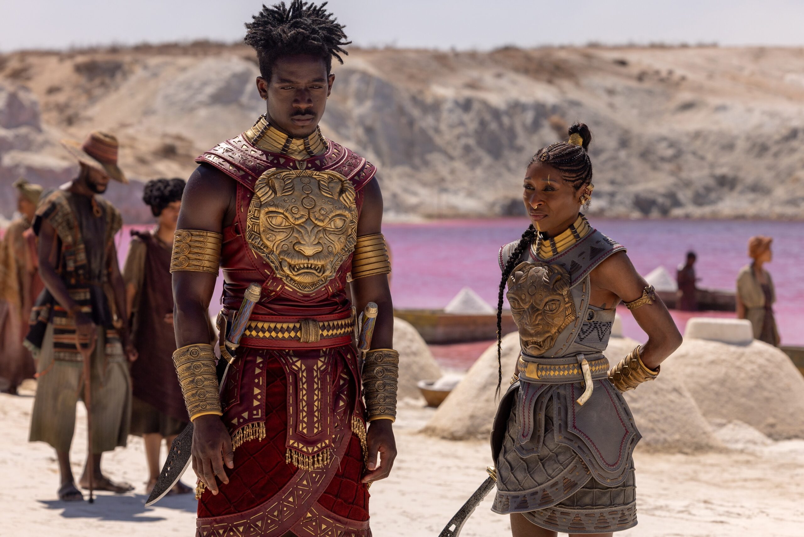 Damson Idris as Prince Inan and Cynthia Erivo as Admiral Kaea in matching red and grey leather armour with gold lion medallions on the chest.