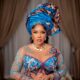 Iyabo Ojo in a detailed turquoise and purple illusion corset gown, showcasing the structured metallic gele and gold choker necklace.