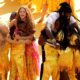 Burna Boy and Shakira embrace members of the Ghetto Kids in a group hug on the yellow stage following their halftime show performance.