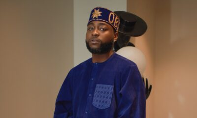 Davido wearing a royal blue velvet tunic, gold embroidered silk wrapper, and customised OBO velvet cap for a traditional Nigerian event.