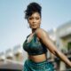Nigerian actress Osas Ighodaro wearing a metallic green square-neck crop top with branded elastic waistband by Tubo RTW, styled with a curly updo and chunky gold arm cuffs.