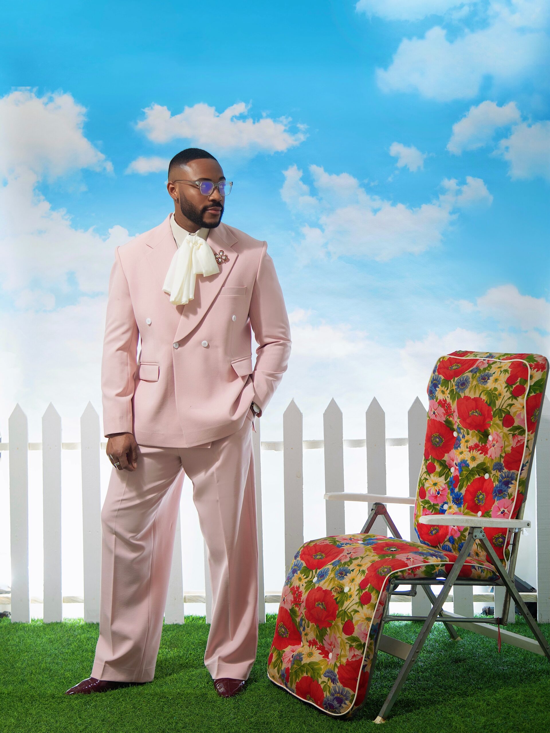 Kola Omotosho wearing a dusty pink double-breasted Emmy Kasbit suit styled by Yomo Daj with an ivory bow blouse and oxblood dress shoes.