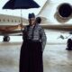Ebuka Obi-Uchendu in a long-sleeved lattice sequin tunic and floor-length black velvet wrapper skirt paired with zebra-print leather loafers inside an aviation hangar for Big Brother Naija Season 11.