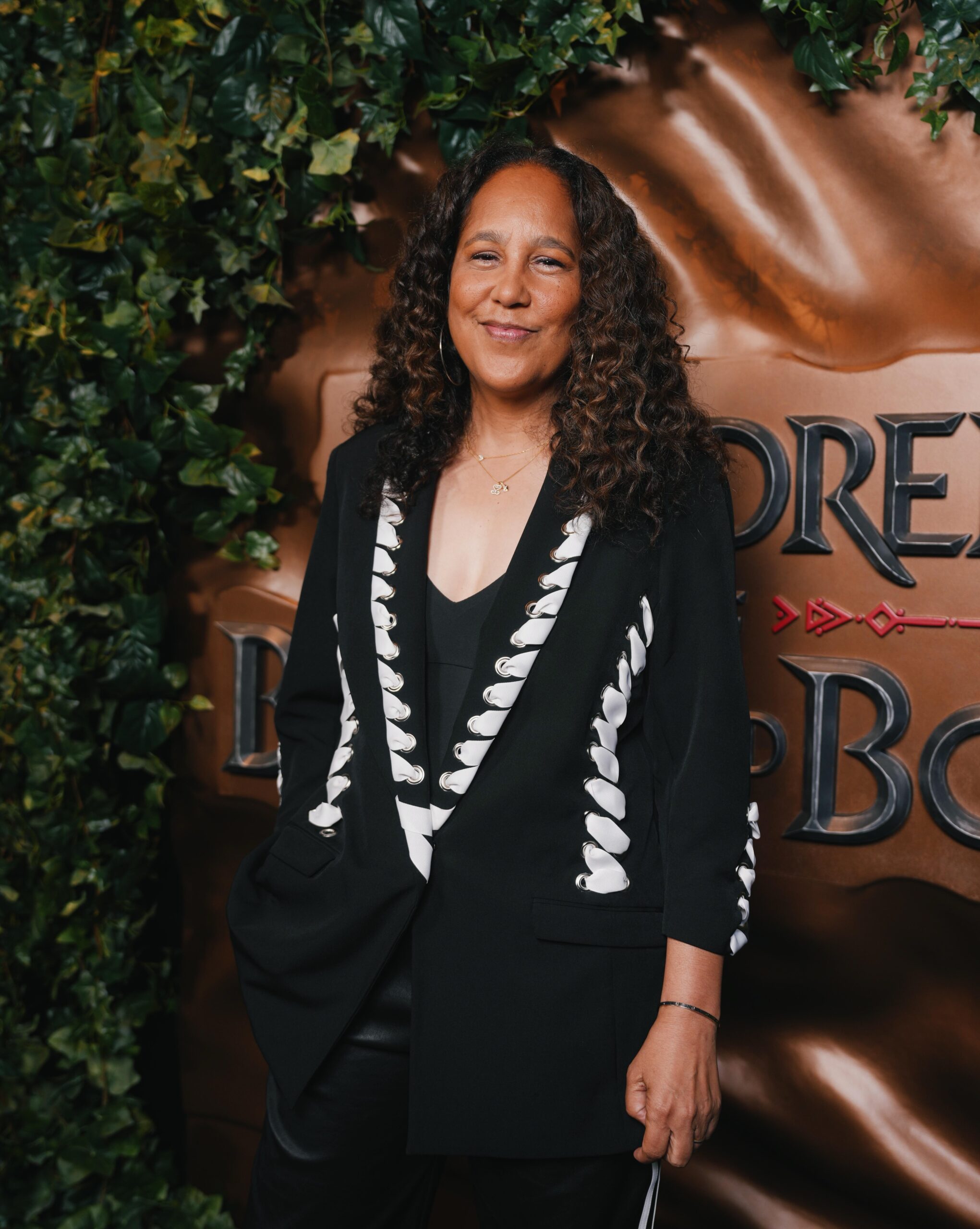 Director Gina Prince-Bythewood wearing a black blazer standing near the Children of Blood and Bone press backdrop in Brooklyn.