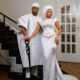 Femi Atere resting his hand on a carved lion cane alongside Veekee James wearing a pearl-beaded white gown and white gele.