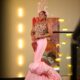 Veekee James holding a grape cluster prop in a custom Veekee James brand pink mermaid gown with puffed hem for baby Eliana Atere Fruit Garden reception theme