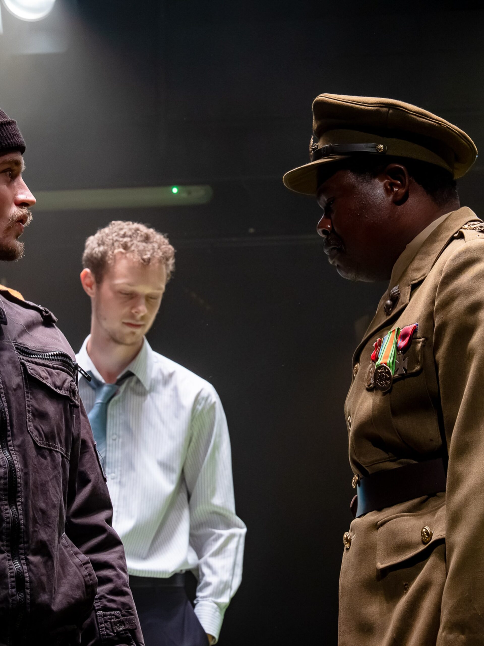 Debo Adedayo in a 17th-century military officer uniform standing face-to-face with a fellow actor during a dramatic scene in the historical play 55 Days in London.